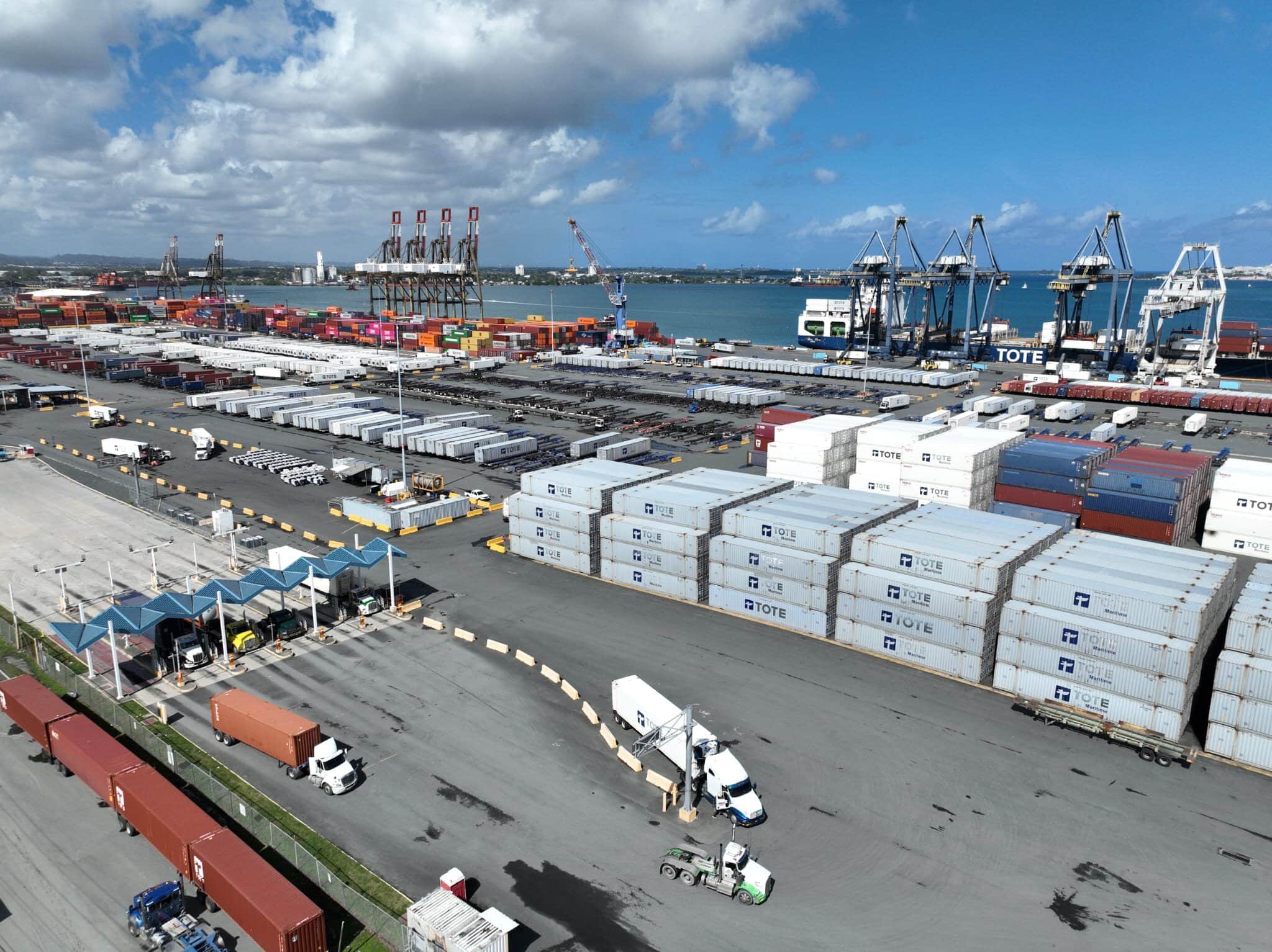 Container yard with stacked shipping containers and cranes at a busy port.